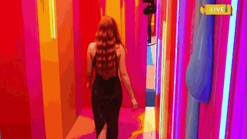 a woman in a black dress is walking down a colorful hallway with a live sign .