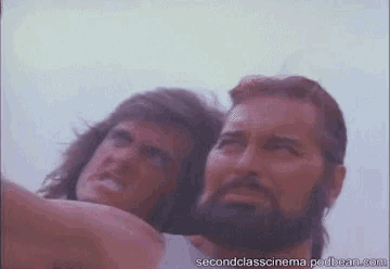 a man with a beard is standing next to another man with a long haired man .