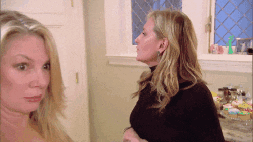 two women standing next to each other in a kitchen