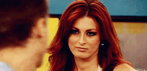 a woman with red hair is making a funny face while talking to a man .