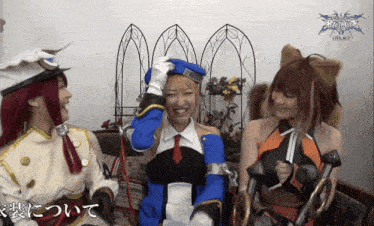 a woman in a blue and white costume is smiling while sitting next to two other women
