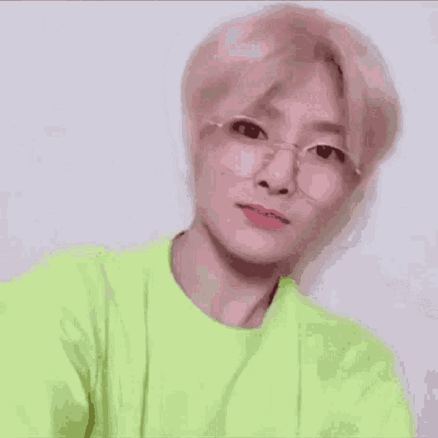 a close up of a person wearing glasses and a neon green shirt .