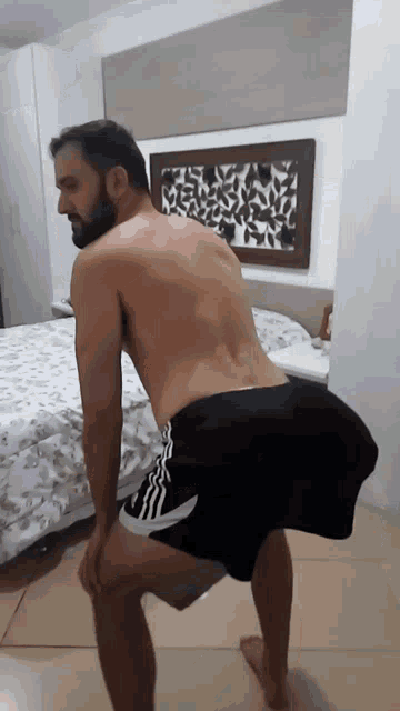 a shirtless man in black shorts is squatting down