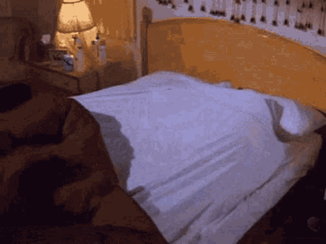 a bed with a white blanket and a lamp on it