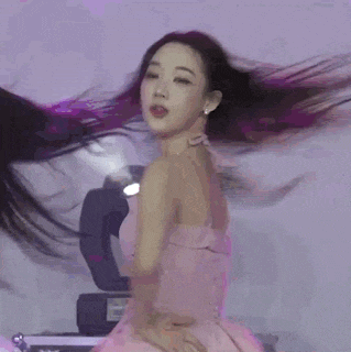 a woman in a pink dress is standing on a stage in front of a spotlight .