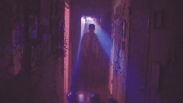a man is walking down a hallway decorated with christmas lights .