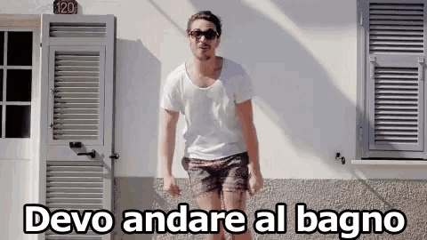 a man standing in front of a building with the words devo andare al bagno written below him