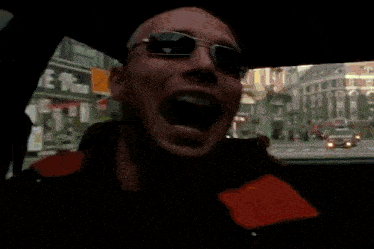 a bald man is smoking a cigarette while wearing a black jacket with the word rolling stones on it
