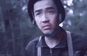 a man wearing a helmet and suspenders is looking at the camera in a dark forest .