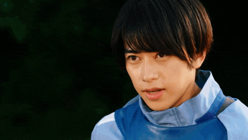 a young man in a blue jacket is making a funny face and pointing at the camera