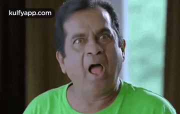 a man wearing a green shirt is making a funny face .