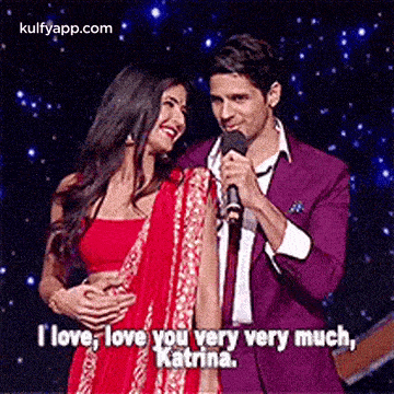 a man in a purple suit is holding a microphone while a woman in a red dress stands next to him .