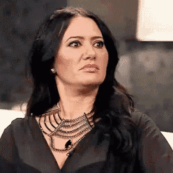 a woman wearing a black shirt and a necklace is making a face .