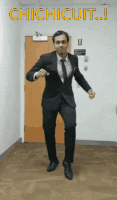 a man in a suit and tie is dancing in front of a door that says " chichicuit "