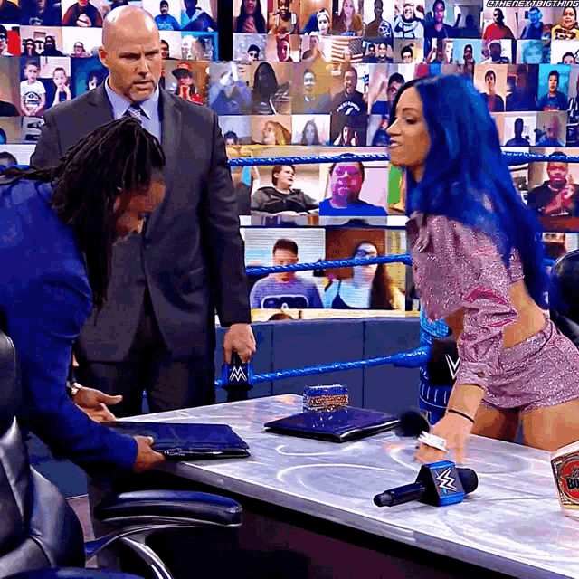 a woman with blue hair is sitting at a table with a man in a suit