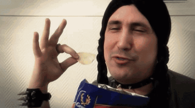 a man in a black hat is holding a bag of crisps