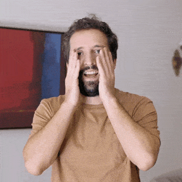 a man with a beard is covering his eyes with his hands