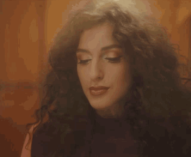 a woman with curly hair is wearing a purple sweater