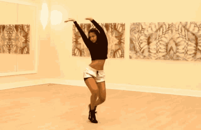 a woman is dancing in a room with paintings on the walls