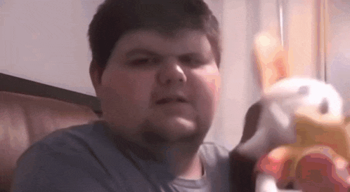 a fat man with a beard is holding a stuffed animal in his hand .