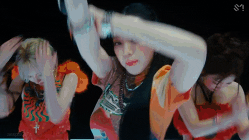 a group of women are dancing together on a stage in a dark room .