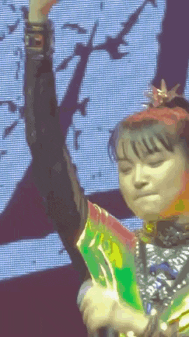 a girl with a crown on her head is singing into a microphone with her eyes closed