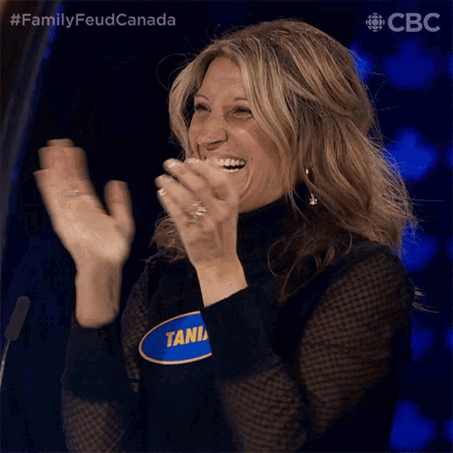 a woman applauds while wearing a black turtleneck and a blue shirt with the number 1 on it