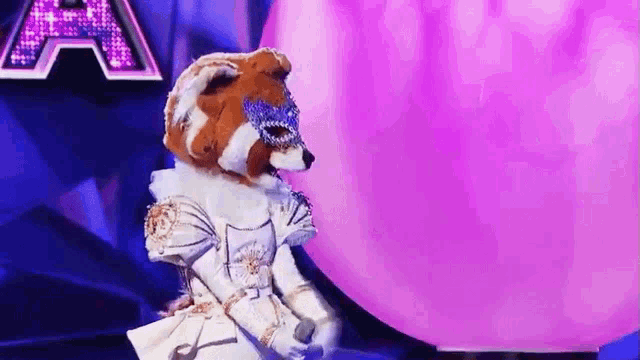 a masked animal is standing in front of a purple balloon .
