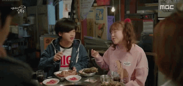 a group of people are sitting at a table eating food and drinking .