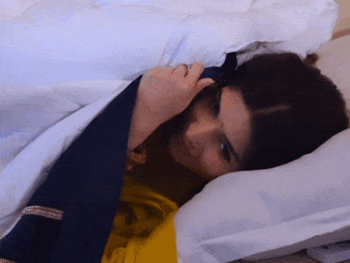 a woman with a nose ring is laying on a bed with white sheets