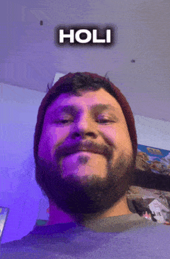 a man with a beard wearing a beanie and smiling with the word holi above him
