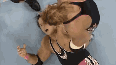 a wrestler wearing a black and pink outfit with the letter s on the back