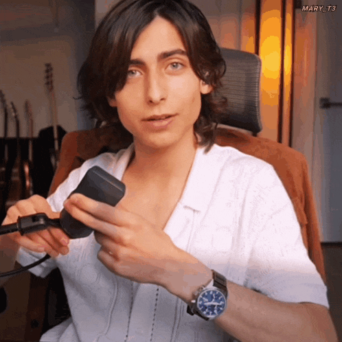 a man wearing a white shirt and a blue watch is holding something in his hands