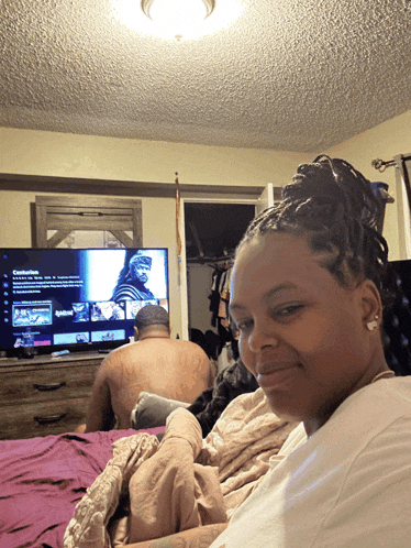 a woman sits in front of a tv that says netflix on the screen