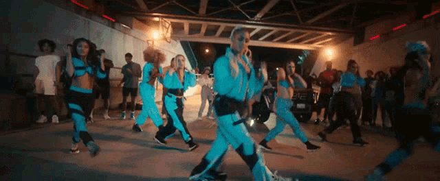 a group of people are dancing under a bridge at night .