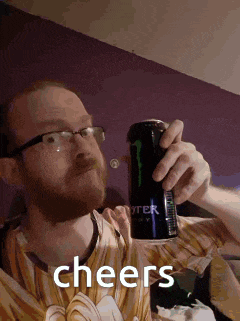 a man wearing glasses is holding a monster energy drink