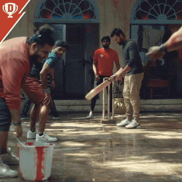 a group of men are playing a game of cricket in a courtyard
