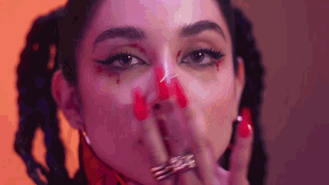 a close up of a woman with red paint on her face covering her mouth .