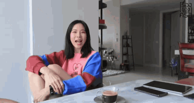 a woman sits at a table with a cup of coffee in front of her and the word son on the bottom right