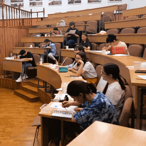 a group of people sitting at tables in a lecture hall