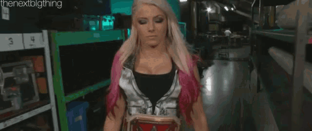 a woman with blonde hair is standing in a warehouse holding a box .