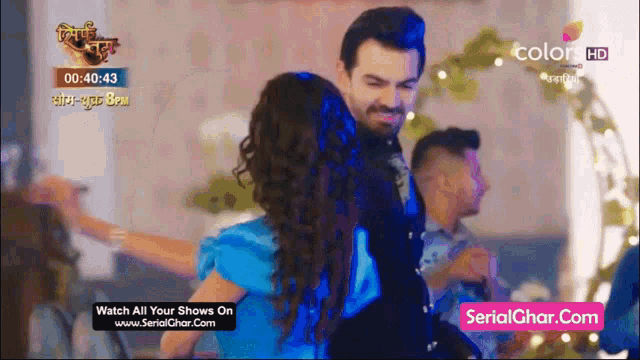 a man and a woman are dancing in front of a screen that says serialghar.com
