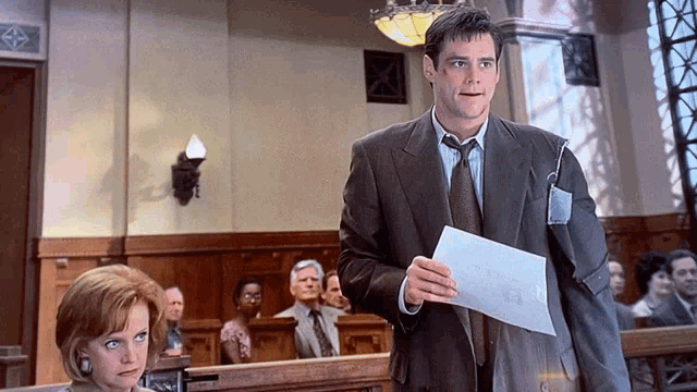 a man in a suit and tie holds a piece of paper in front of a woman in a courtroom