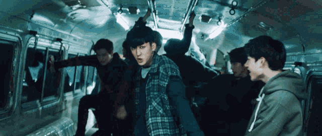 a group of young men are riding a bus and one of them is wearing a plaid shirt
