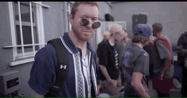 a man wearing sunglasses and an under armour backpack