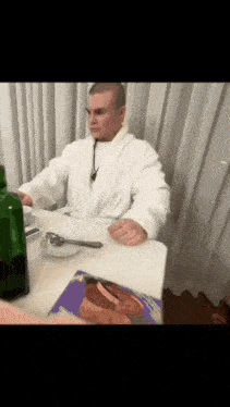 a man in a bathrobe is sitting at a table