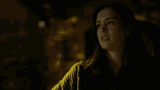 a woman in a dark room looks up at the sky