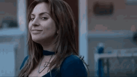 a close up of a woman wearing a choker necklace and a blue shirt .