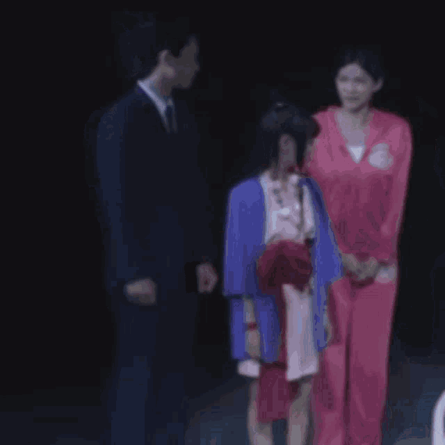 a blurry picture of a group of people including a man in a suit and a woman in a pink dress