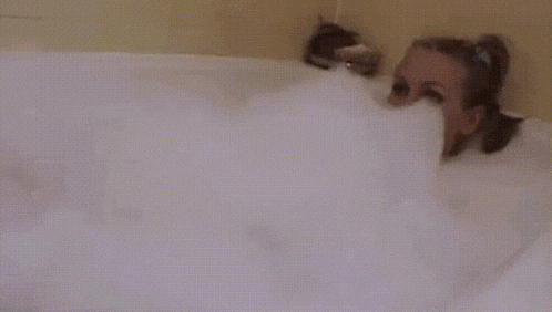 a woman is taking a bath in a bathtub filled with bubbles